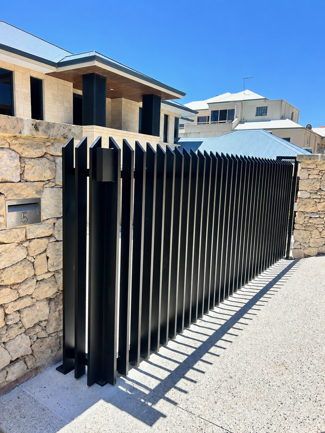 Black aluminium sliding gate with angled vertical battens