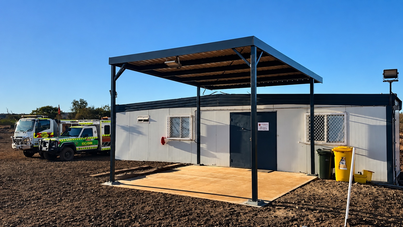 Dark steel entrance canopy beside a site building
